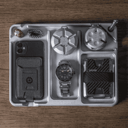 Organized EDC tray with watch, wallet, and accessories on a wooden surface.